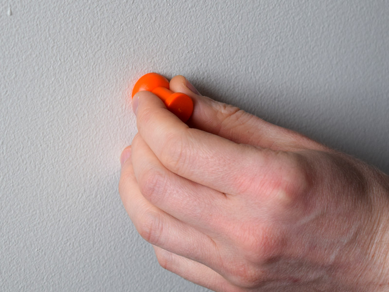Magnetic thumbtack being used as a stud finder magnet