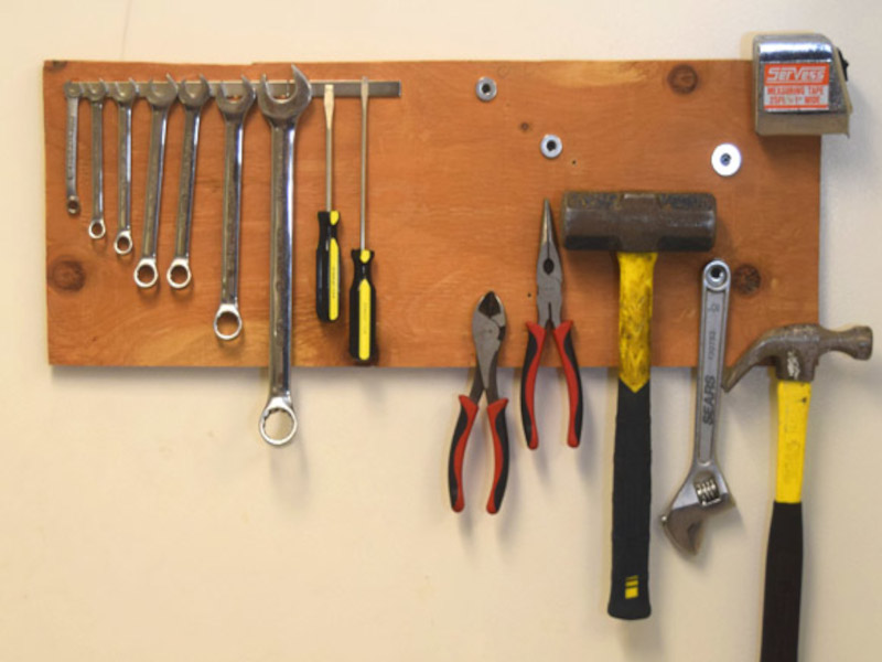 Many different tools hanging on wooden magnetic wall tool holder