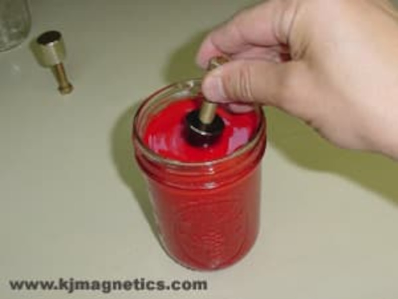 Magnet being dipped into liquid rubber