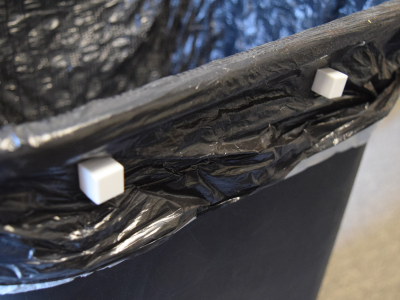 White plastic coated block magnets holding trash bag to trashcan