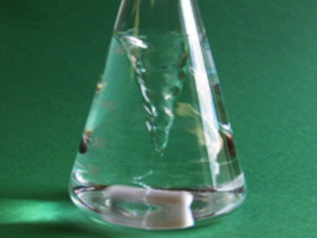 Magnetic stir bar being used to stir liquid inside of a chemistry beaker.
